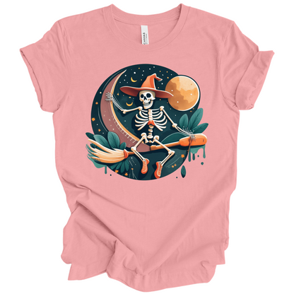 Pink halloween t-shirt with a skeleton on a broomstick wearing a witch hat in the night time.