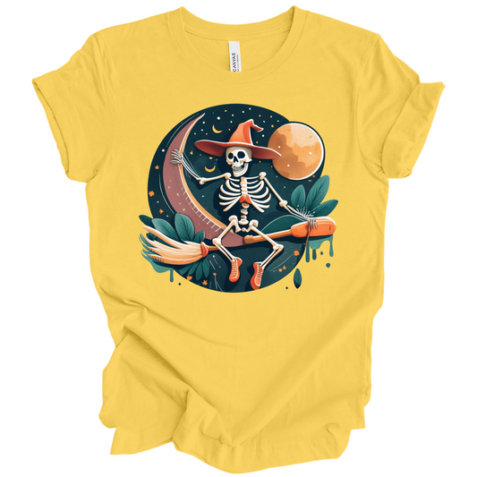 Yellow halloween t-shirt with a skeleton on a broomstick wearing a witch hat in the night time.